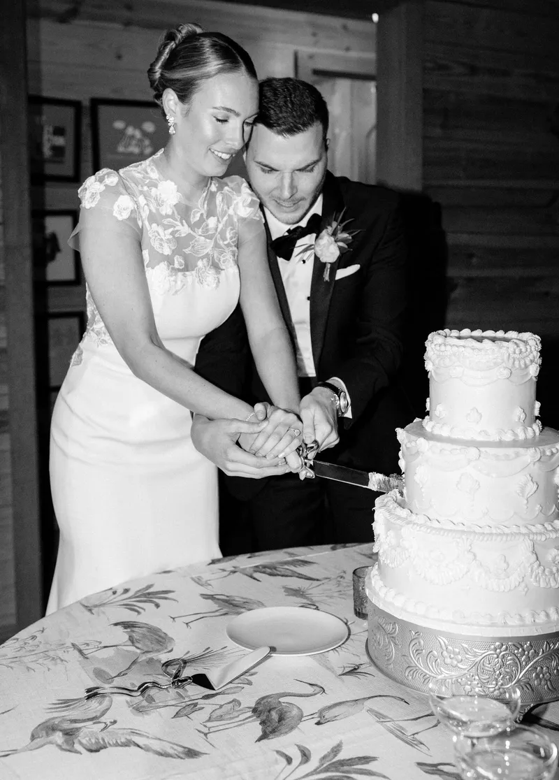 Avery and Carson cutting their wedding cake, in black and white